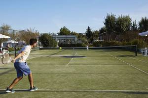 Tennisplatz im Hotel Capo Di Corfu mit Spielern, die Tennis spielen.