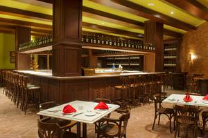 Innenansicht der Bar im Makadi Spa Hotel mit Holztischen, Stühlen und einer Theke voller Flaschen.