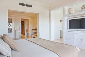 Das geräumige Schlafzimmer im Makadi Spa Hotel mit weißem Bettzeug, Kissen und einem Fernseher.
