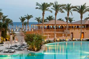 Makadi Spa Hotel Poolbereich bei Nacht mit Palmen und Sonnenliegen