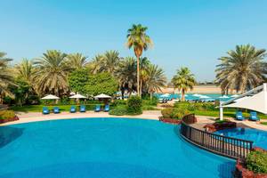 Außenpool des Sheraton Abu Dhabi Hotel & Resort mit Sonnenliegen und Palmen