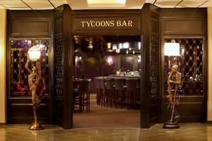 Eingang des Tycoons Bar im GrandResort Limassol mit zwei Statuen und einer offenen Tür.