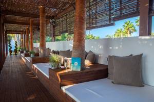 Lounge-Sofas auf der Terrasse des GrandResort Limassol mit Blick auf Palmen und Meer.