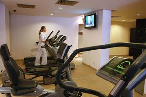 Frau im weißen Outfit läuft auf einem der drei Tretmühlen im Fitnessstudio des GrandResort Limassol.