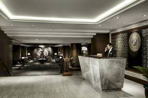 Empfangsbereich im Banyan Tree Bangkok mit Marmortheke und Angestelltem am Telefon
