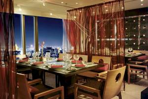 Innenansicht des Restaurants im Banyan Tree Bangkok mit Tisch, Stühlen und Aussicht auf die Stadt bei Nacht.