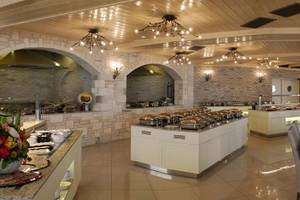 Innenbereich des Cactus Royal Hotels mit vielen Tischen und Stühlen, Buffets und dekorativen Kronleuchtern.