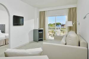 Ein modernes Hotelzimmer mit zwei Betten, einem Fernseher, einem Sofa und einer Terrasse.