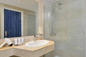 Badezimmer im Sol Guadalupe Hotel mit großer Dusche, Waschbecken und Spiegel.