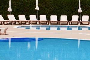 Schwimmbeckenbereich des Sol Guadalupe Hotels mit weißen Liegestühlen und Sonnenschirmen.