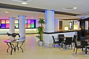 Lobby des Sol Guadalupe Hotels mit bunten Säulen und modernen Möbeln.