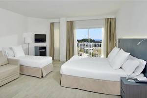 Ein modernes Hotelzimmer mit zwei Betten, einer Couch, einem Fernseher und einer Terrasse mit Blick auf das Meer.