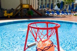 Schwimmbad im Princess Inspire Tenerife Hotel mit einem roten Basketballkorb und einer Rutsche im Hintergrund.