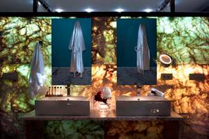 Badezimmer im Royal Blue Resort mit zwei Waschbecken und Spiegeln an einer Marmorwand.