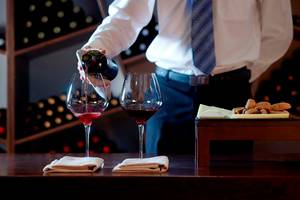 Kellnerin gießt Rotwein in zwei Gläser auf dem Royal Blue Resort