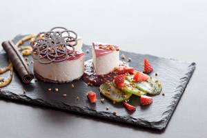 Dessertplatter im Barcelo Fuerteventura Castillo mit zwei Käsekuchen, Früchten und Schokoladenverzierungen.