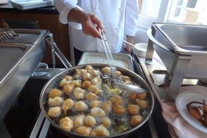 Koch im Platanista Hotel frittiert gefüllte Kugeln in einer Pfanne.