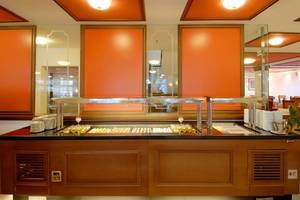 Buffetbereich im Platanista Hotel mit orangefarbenen Wänden und vielen Speisen.
