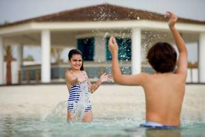 Kinder spielen im Wasser vor einer Villa im Intercontinental Abu Dhabi.