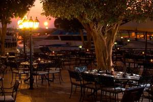 Außenbereich des Restaurants des Intercontinental Abu Dhabi mit stimmungsvollen Lampen und Tischen im Freien