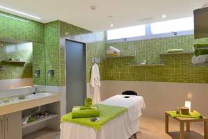Massage-Behandlungsraum im Alexandre Hotel Troya mit grünen Fliesen und einer Liege.