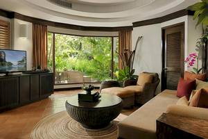 Rayavadee Hotel Wohnzimmer mit Couch, Tisch, Fernseher und großem Fenster mit Blick auf die Natur.