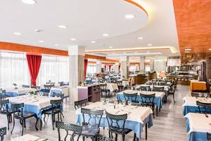 Innenbereich des Restaurants im Alexandre Hotel Troya mit gedeckten Tischen und Stühlen.