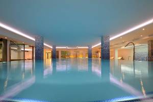 Innenpool des Alexandre Hotel Troya mit blauen Wänden und beleuchteten Säulen.