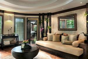 Wohnzimmer im Rayavadee Hotel mit einem großen Sofa, Kissen, einem Tisch und einem Spiegel.