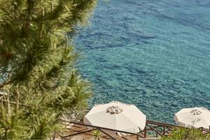 Candia Park Village Terrasse mit zwei weißen Sonnenschirmen und Blick auf das Meer.