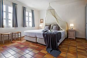 Schlafzimmer im Candia Park Village mit Bett unter Moskitonetz und zwei Nachttischen