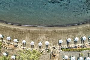 Luftaufnahme von Strand und weißen Sonnenschirmen im Candia Park Village Hotel.