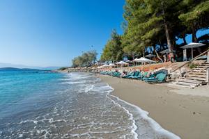 Candia Park Village Strand mit Sonnenliegen und Schirmen, klares Wasser und blauer Himmel