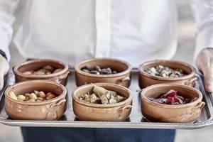 Servierteller mit kleinen Schalen gefüllt mit verschiedenen Vorspeisen wie Oliven, Bohnen und Artischocken.