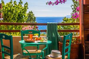 Balkon des Candia Park Village Hotels mit Blick auf das Meer und grüner Vegetation.