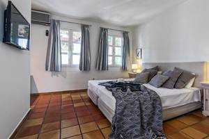 Schlafzimmer im Candia Park Village Hotel mit einem großen Bett, Nachttischen und Wandleuchten.