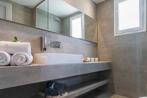 Badezimmer im Candia Park Village mit weißem Waschbecken, Handtüchern und Fliesenwänden.