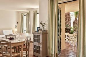 Innenansicht eines Zimmers im Candia Park Village Hotel mit einem Bett, Tisch und einem offenen Balkon