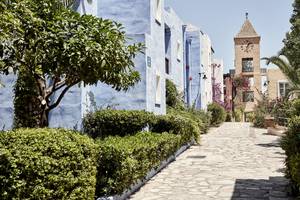 Candia Park Village Hotel Weg mit blauen Gebäuden und einem Turm im Hintergrund.