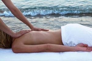 Eine Frau genießt eine Massage am Strand in Candia Park Village.