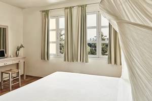 Schlafzimmer im Candia Park Village Hotel mit Bett, Nachttisch und Fenstern.