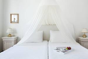 Zwei Betten im Candia Park Village mit weißen Laken, Kissen und einer durchsichtigen Himmelbett-Bettwäsche.