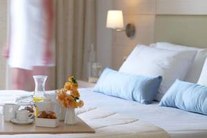 Frühstückstisch im Hotelzimmer von Porto Bello Beach mit Blumen, Kaffee und Croissants.