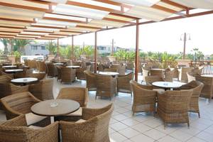 Terrasse des Porto Bello Beach Hotels mit vielen Tischen und Stühlen im Freien