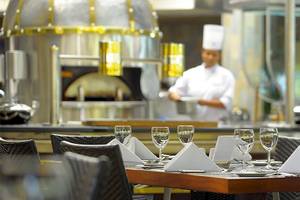 Restauranttisch im Shandrani Beachcomber Resort & Spa mit Tischwäsche und Gläsern, ein Koch im Hintergrund