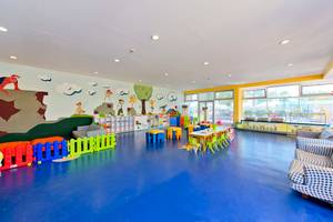 Kinderspielzimmer im Concorde De Luxe Resort mit farbigen Wänden, Tischen, Stühlen und Spielzeug.