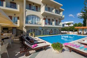 Außenbereich des Kalyves Beach Hotels mit Swimmingpool und Sonnenliegen.