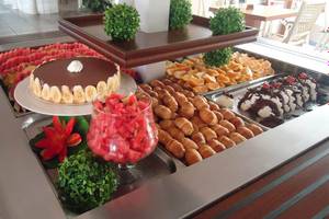 Buffet-Tisch im Kalyves Beach Hotel mit verschiedenen Desserts, Früchten und Getränken.