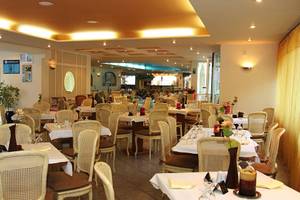 Innenansicht des Restaurants im Kalyves Beach Hotel mit vielen gedeckten Tischen und Stühlen.