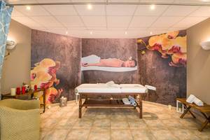 Spa-Massageraum im Kalyves Beach Hotel mit Massageliege, Deko und Wandbildern.
